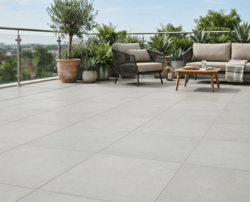 Modern rooftop terrace with large grey tiled floor, potted plants, and beige outdoor seating around a wooden coffee table.